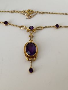 A lovely antique Art Nouveau amethyst necklace in a rich 14 karat buttery yellow gold mounting. This delicate design is a little Gem with it's simple yet very elegant design centered around an antique, faceted, deep purple, oval amethyst. The fine chain has stations of 6 round bezel set amethysts who's color matches the intense purple of the center stone. The sizes are slightly tapered for a beautiful symmetry  There is an extra safety link chain to reinforce the strength of this delicate piece. Vintage Amethyst Necklace, Cheap Antique Oval Jewelry, Formal Purple 14k Gold Necklace, Antique Oval Purple Jewelry, Antique Amethyst Jewelry Stamped 14k, Antique Oval Gemstone Necklace, Antique Purple Oval Jewelry, Antique Oval Purple Necklaces, Antique Purple 14k Stamped Jewelry