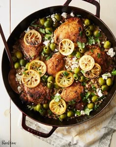 a pan filled with chicken and olives on top of a table