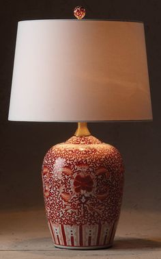 a red and white vase with a lamp on it