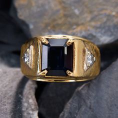 This masculine ring is centered with one (1) emerald cut natural sapphire set into a four-prong setting. The shoulders of the ring are each accented with one (1) round brilliant cut diamond bead set into a white gold triangular shaped setting. The shoulders of the ring have a Florentine finish. The ring measures 13.8mm at the top, rises 6.6mm above the finger, tapering to 5.6mm wide and 1.2mm thick at the base of the shank. The piece is crafted in 14k yellow gold and is currently a size 11.75. Masculine Rings, Antique Engagement Rings Sapphire, Estate Jewelry Rings, Wedding Ring Diamond Band, Bead Set, Sapphire Diamond Ring, Antique Engagement Rings, European Cut Diamonds, Sapphire Engagement