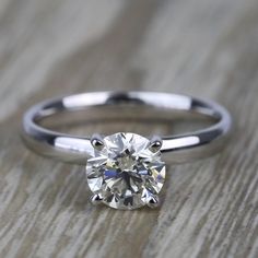 a white diamond ring sitting on top of a wooden table