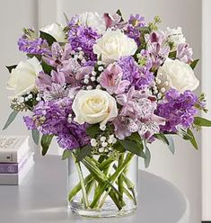 a vase filled with white and purple flowers on top of a table next to a book