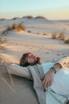 a man laying in the sand with his eyes closed