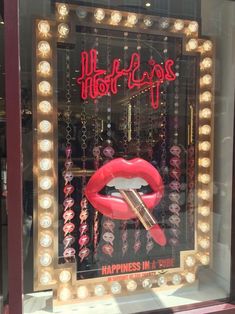 a lighted display window with a red lipstick on it's lips and the words happiness in front