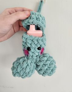 a hand holding a crocheted stuffed animal with a pacifier in it's mouth