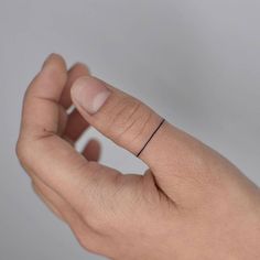 a person's hand with a small black band on their left wrist and the ring is