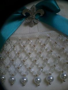 a close up of a brooch with pearls and a blue ribbon on the back