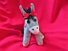 a stuffed donkey with a red bow on it's head sitting on a pink cloth