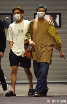 two men walking down the street wearing face masks