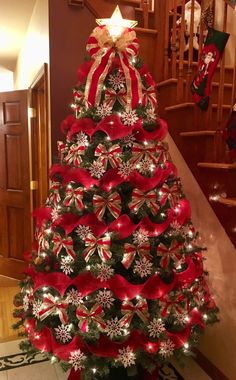 a christmas tree decorated with red ribbon and bows