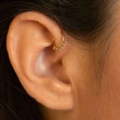 a woman's ear is shown with two small gold rings