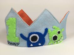 a blue and green felt crown with monsters on it