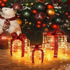 two presents are wrapped in red ribbon and placed next to a christmas tree with lights