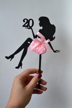 a person holding up a cake topper with the number twenty on it's side