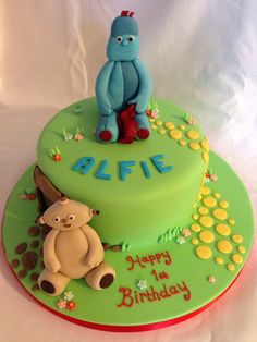 a green birthday cake with an image of a blue monster and a teddy bear on top