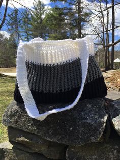 a black and white bag sitting on top of a rock