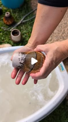 a person holding something in their hand over a sink filled with water and other items