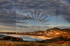 the sun shines brightly through clouds over an ocean and town on top of a hill