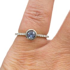 a woman's hand with a ring on it and a blue stone in the middle