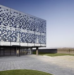 a large building with many windows on top of it's sides and grass in the foreground