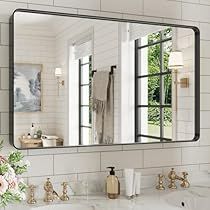 a bathroom sink with a mirror above it and flowers on the counter top next to it