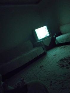 a small tv sitting on top of a bed in a dark room