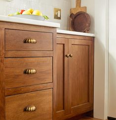 a kitchen with wooden cabinets and white counter tops, along with a cutting board on top of the cabinet