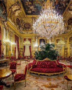 an elaborately decorated room with chandelier and red couches