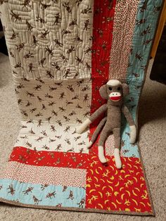 a stuffed monkey sitting on top of a patchwork quilt