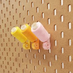 three spools of thread on a pegboard with holes in the wall behind them