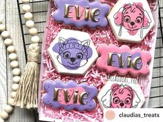 decorated cookies in the shape of dogs and cats on a pink tray with tassels