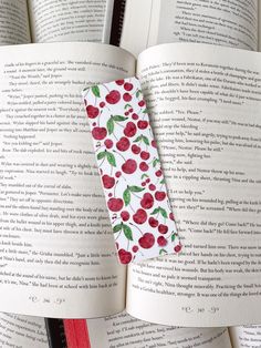 an open book with cherries on it and a red pen sticking out of the pages