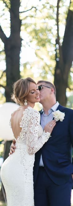 a bride and groom kissing in front of trees