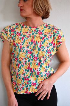 "Garden of Delights Top - Size Medium (size on vintage tag 12).  Short cropped blouse with an amazing bright floral print.  Top buttons up the back and is 100% rayon.  Shoulder pads have been left in but easily removable.   Excellent Vintage condition.  Freshly laundered and ready to wear! Measurements are taken while garment lie flat. Please double bust, waist and hips for best fit. Label: Michelle Stuart Bust: 21\" Waist: 18\" Sleeve Length: 9\" Neck Width:  8.5\" Length from top of shoulder t Vintage Summer Tops With All Over Print, Spring Patterned Top With Vintage Print, Spring Patterned Tops With Vintage Print, Patterned Vintage Print Tops For Spring, Vintage All-over Print Top For Spring, Green Vintage Print Blouse For Spring, Spring Green Blouse With Vintage Print, Retro Patterned Tops For Spring, Vintage Short Sleeve Tops With Vibrant Print