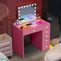 a pink vanity table with lights on it and a mirror in front of the desk