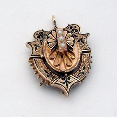 "Victorian era ornate 14 K (.585) rose gold locket pendant, decorated with Seed Pearls and black enamel. It was a combination of brooch and pendant, but the pin was removed (in current condition it is a pendant). This magnificent antique locket is 1 1/2\" long, 1 1/8\" wide and weighs 12.3 grams. The pendant is slightly bent, and there is some enamel loss  due to age. EA2188" Ornate Engraved Brooch, Victorian Enamel Locket Jewelry, Elegant Medallion Shaped Brooch Jewelry, Formal Enamel Locket Jewelry, Elegant Medallion Shaped Brooch, Victorian Gold Brooch With Locket, Victorian Gold Locket Brooches, Ornate Gold Locket Brooches, Antique Engraved Medallion Brooches