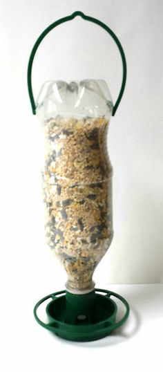 a bird feeder filled with birdseed on top of a white table next to a green stand