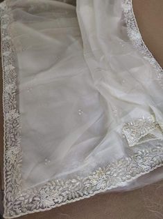 This is a fascinating pure organza silk saree in gorgeous white color, monochrome look. Saree features a dazzling beads and pearl work embroidery of floral design throughout the edges of the saree. Simple pearl work is twinkling all over the body of the saree. The beads and pearl embroidery are delicately hand embellished. Organza is a lightweight plain weave fabric. The pure organza attributes to a very comfy and flowy drape. Organza is considered as one of the most stylish and glamorous wear. Semi-stitched White Organza Saree, Elegant Off White Dupatta In Traditional Drape, Elegant Off White Traditional Dupatta, Elegant Organza Blouse Piece, Elegant Off White Silk Dupatta, Elegant Off-white Silk Dupatta, Organza Saree With Pearl Embroidery For Party, Elegant Organza Dupatta With Pearl Embroidery, Elegant Off White Saree With Cutdana