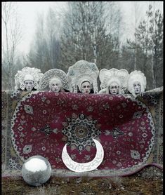 a group of women with head coverings on their heads sitting in front of a rug