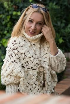 a woman in a white crocheted sweater and sunglasses talking on her cell phone