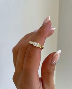 a woman's hand holding a gold ring with two small diamonds on the middle