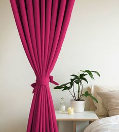 a bedroom with a bed, nightstand and pink drapes