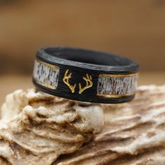 ABOUT THIS RING Material: Black Forged Carbon Fiber, 2 Gold Plated Strips, and a Natural Grain Antler Inlay with a Resin Coating. Color*/Finish: Black and Gold Engraving: Antlers with Gold Oil Width: 8mm *All Antler Rings are 100% Unique so color may vary slightly from image shown. Check out the information about our Antler Rings for more details! QUESTIONS ABOUT SIZING Go to our Ring Sizing Guide for details and important guidance. OTHER BENEFITS FOR YOU FREE ACTIVITY BAND with Purchase (a $55 Hunting Wedding Rings For Men, Antler Ring Men, Antler Engagement Ring, Deer Antler Wedding Band, Deer Antler Wedding, Antler Rings, Antler Wedding Rings, Hunting Wedding, Antler Wedding Band