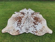 a brown and white cowhide rug on green grass