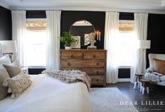 a bedroom with black walls, white curtains and a dresser in the corner next to a bed