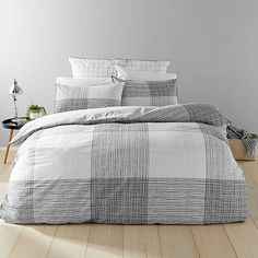 a bed with white and black checkered comforter set on top of wooden flooring