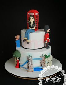 a three tiered cake with figurines sitting on top of it and a red telephone booth