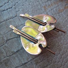 two pieces of metal sitting on top of a blue cloth covered table next to each other