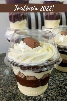 cupcakes with whipped cream and chocolate on top in plastic cups sitting on a counter