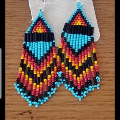 two pairs of beaded earrings on top of a wooden table